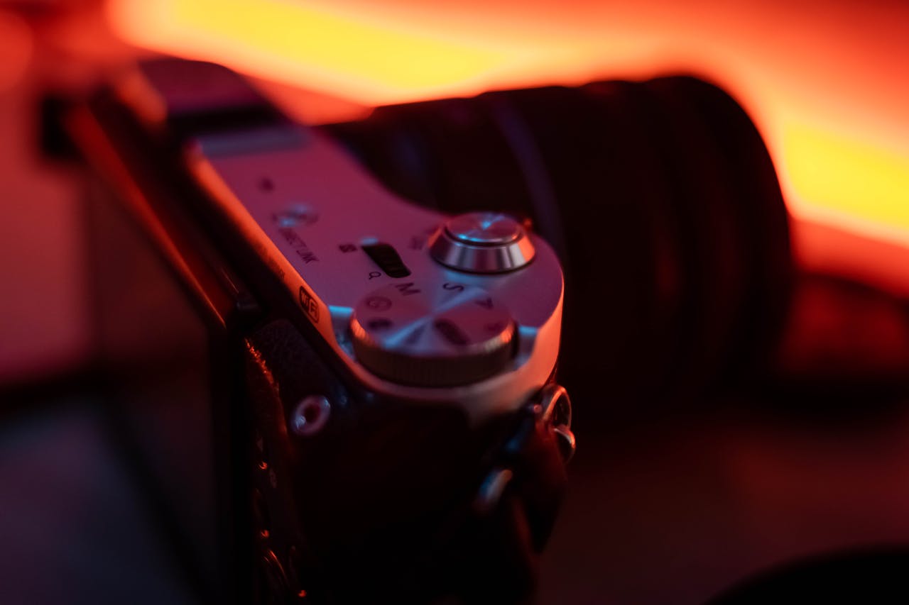 Moody close-up of a digital camera with warm lighting highlighting the dials and design.